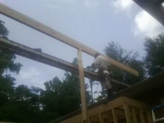Carpenter setting a ridge beam over a new addition frame — Ice Dam Removal by Roofing Brothers in Upland