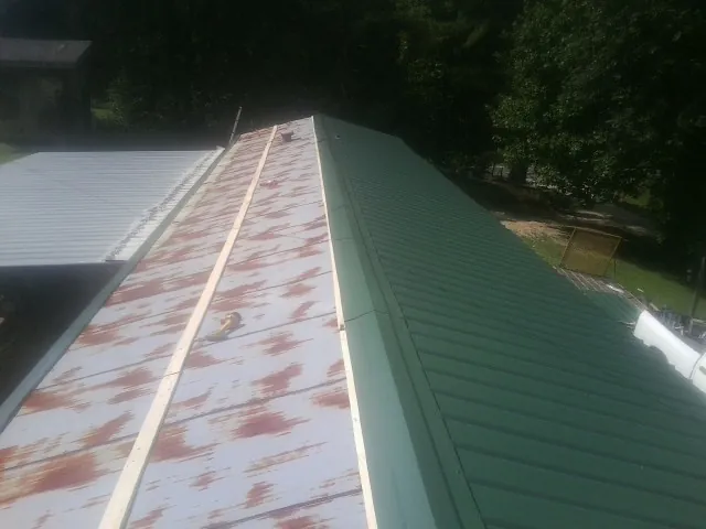 Old rusted panels beside newly installed green metal roofing — Wind Damage Roof Repair by Roofing Brothers in Upland