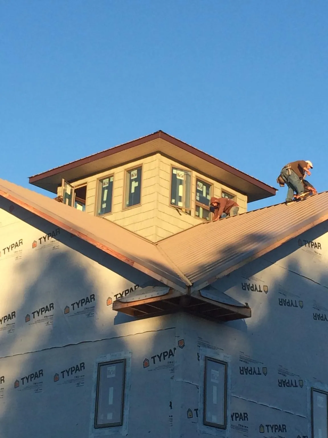 Roofers working around a rooftop cupola on a new metal roof at sunset — Roof Waterproofing in Upland by Roofing Brothers